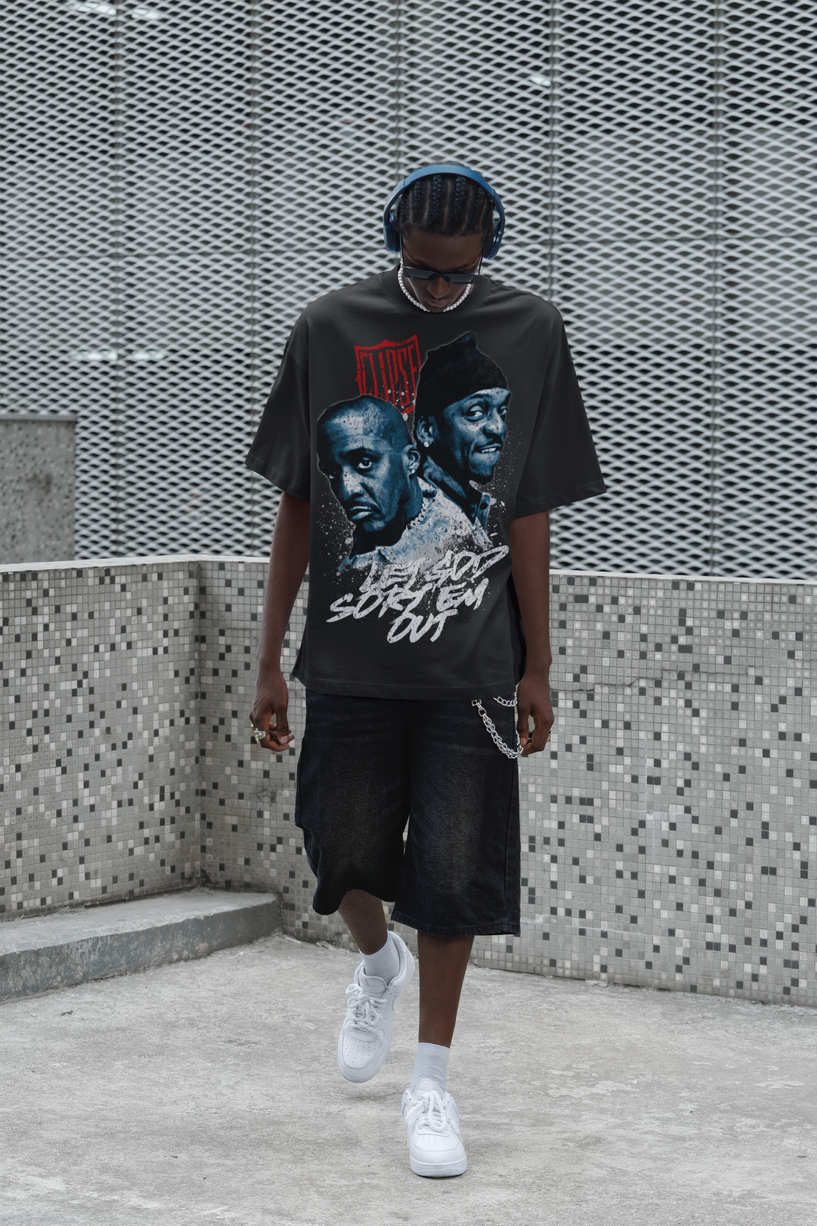 Person wearing a graphic t-shirt with the Clipse, standing against a textured wall.