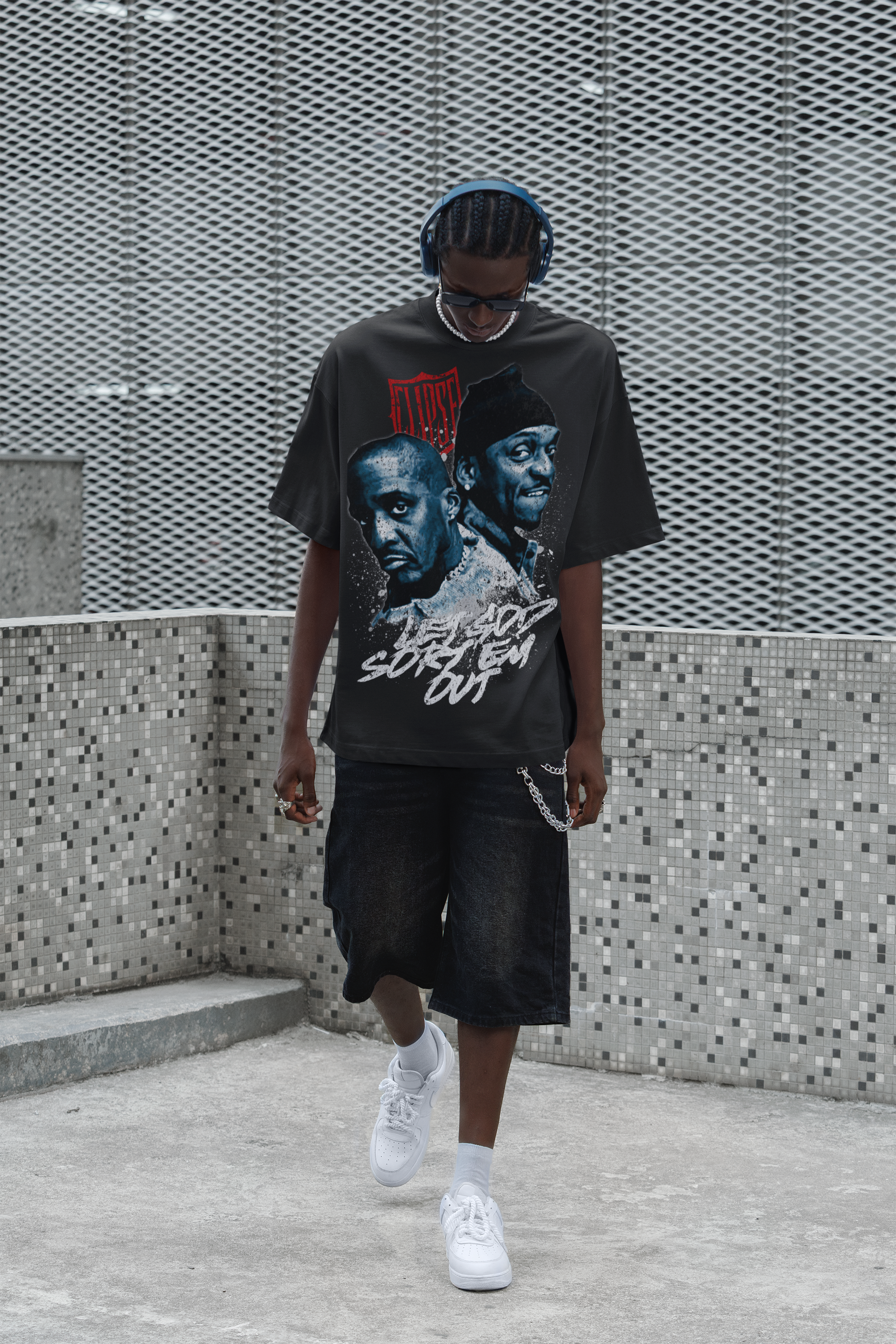 Person wearing a graphic t-shirt with the Clipse, standing against a textured wall.