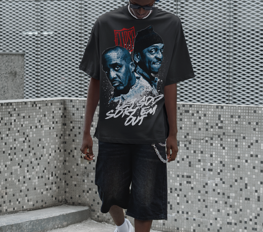 Person wearing a graphic t-shirt with the Clipse, standing against a textured wall.